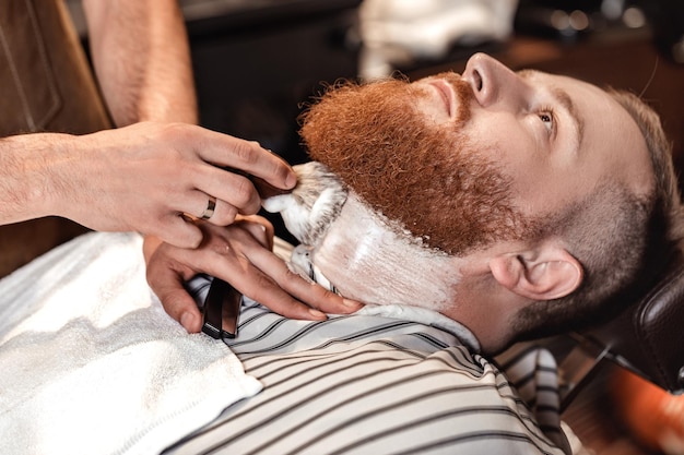 Photo coiffeur et homme barbu dans un salon de coiffure