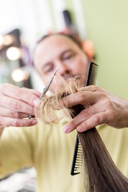 Coiffeur homme coupant les cheveux d'une femme.