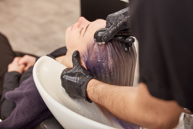 Coiffeur laver les mains shampooing tonifiant sur les cheveux de la femme