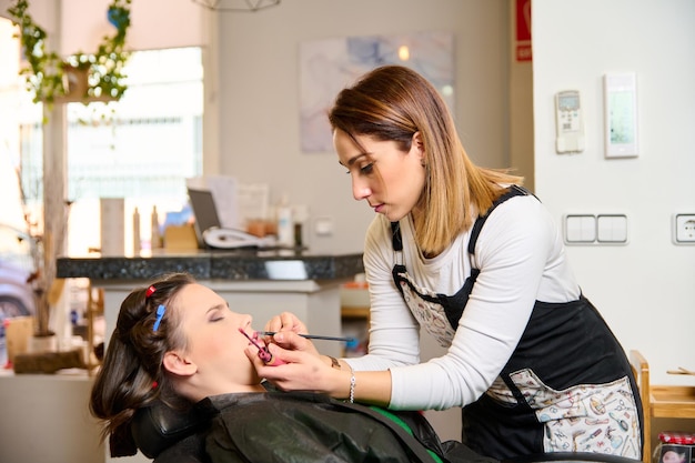 coiffeur maquillant et coiffant une jeune cliente dans un salon de beauté