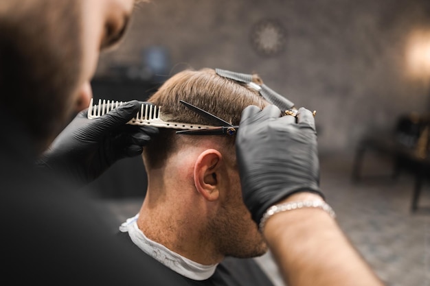 Coiffeur masculin coupant les cheveux des clients masculins dans un salon de coiffure