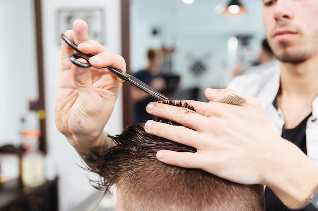 Coiffeur masculin coupant les cheveux à son client dans le salon de coiffure