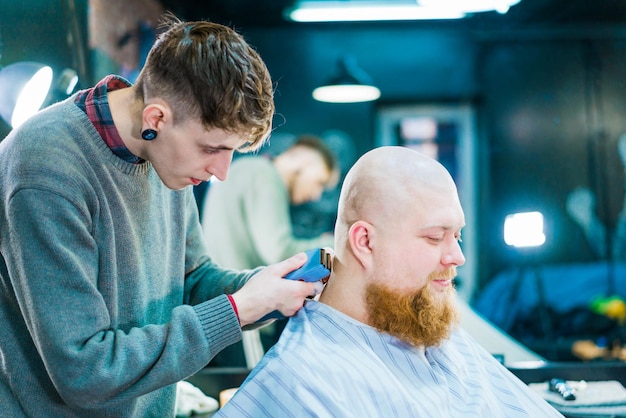 Un coiffeur masculin rasant le cou d'un client avec un rasoir électrique