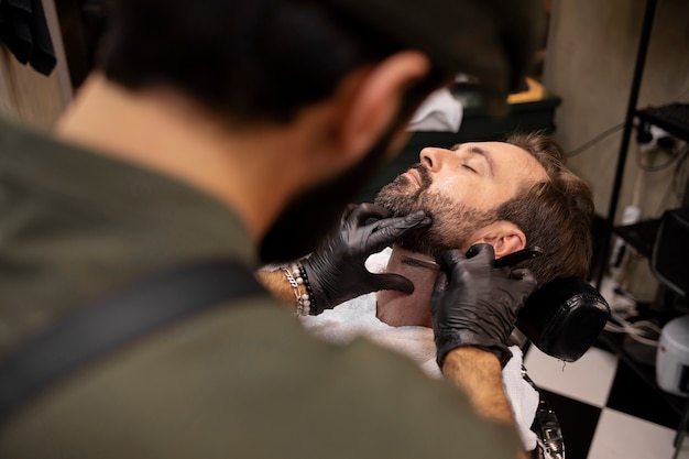 Coiffeur masculin taillant la barbe de son client