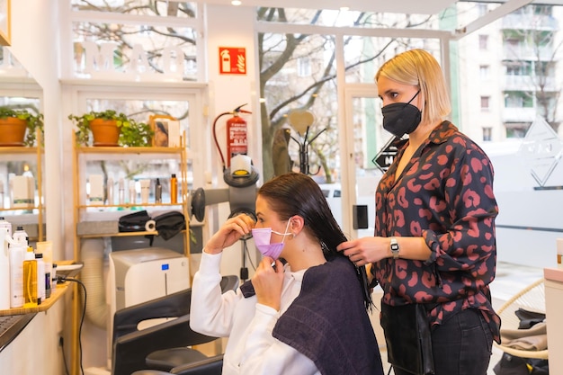 Coiffeur avec masque de protection faciale et le client mettant le masque Mesures de sécurité dans la pandémie de Covid19