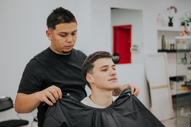 Photo le coiffeur met une robe pour couper les cheveux du garçon