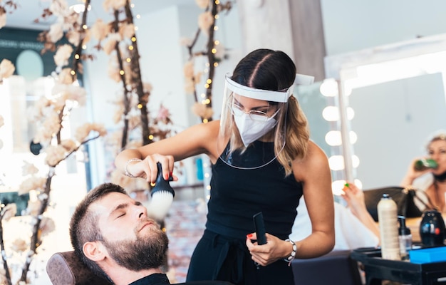 Le coiffeur nettoie les cheveux du visage d'un client à l'aide d'une brosse