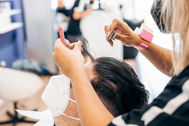 Coiffeur peignant les cheveux d'un homme se faisant couper les cheveux dans un salon de coiffure avec une petite brosse