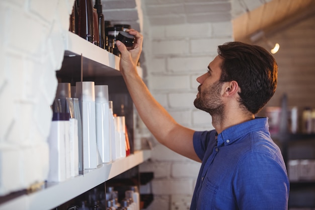 Coiffeur pour hommes sélectionnant le gel de l'étagère