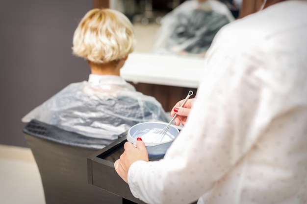 Le coiffeur prépare le colorant dans le récipient