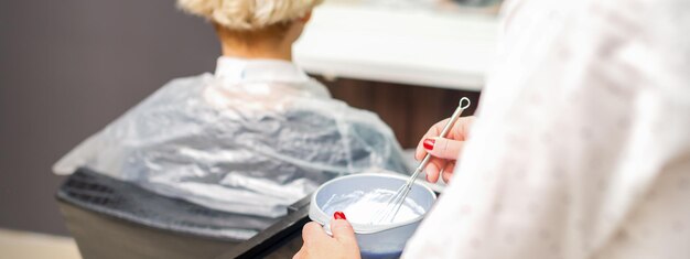 Le coiffeur prépare le colorant dans le récipient