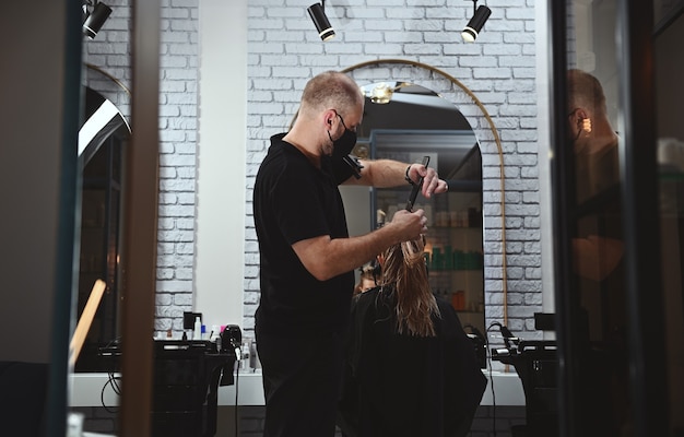 Un coiffeur professionnel au travail dans un salon de beauté, coupant les cheveux d'une femme