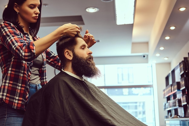 Coiffeur professionnel faisant la coiffure avec un peigne dans un salon de coiffure.