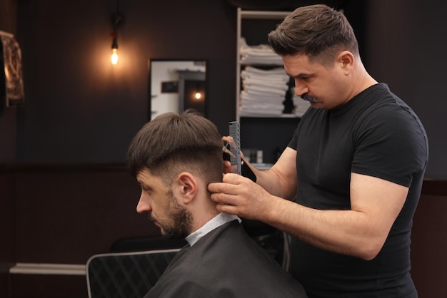 Coiffeur professionnel faisant une coupe de cheveux élégante dans un salon de coiffure