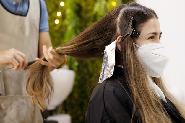 Coiffeur professionnel faisant des reflets à une fille sur le dos dans une chaise de coiffeur