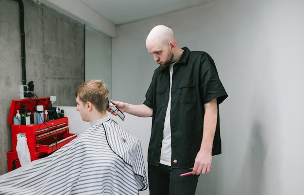 Un coiffeur professionnel fait une coupe de cheveux élégante pour un salon de coiffure aux murs gris