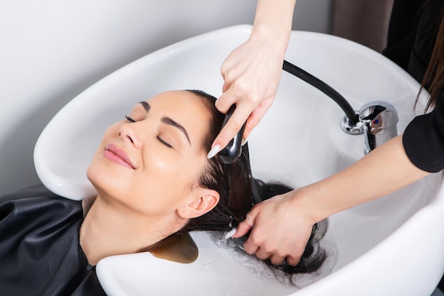 coiffeur professionnel laver les cheveux d'une jeune femme dans un salon de beauté