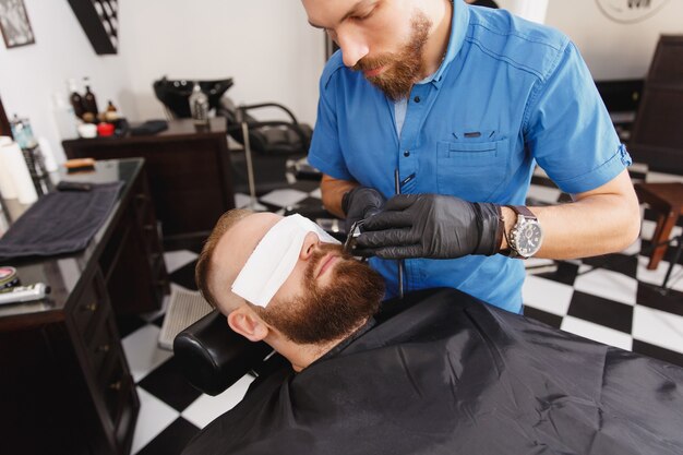 Coiffeur professionnel masculin au service du client par tondeuse