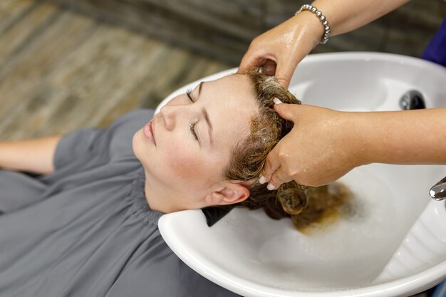 Un coiffeur professionnel méconnaissable lave les cheveux de son client