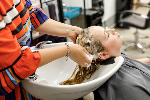 Un coiffeur professionnel méconnaissable lave les cheveux de son client