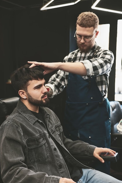 Coiffeur professionnel travaillant avec un client barbu dans un salon de coiffure