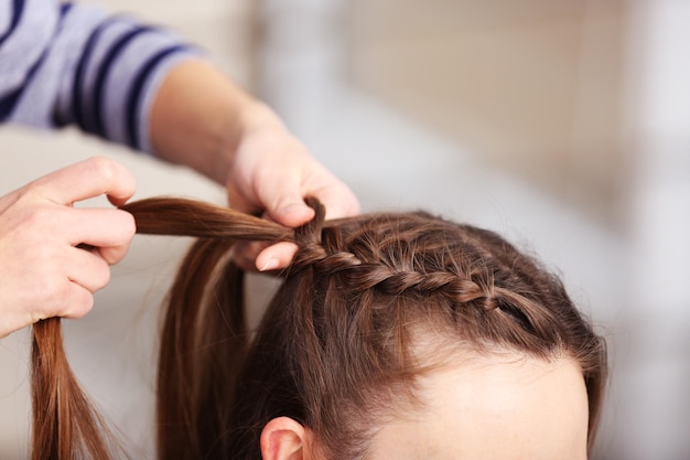 Coiffeur professionnel tressant les cheveux des clients