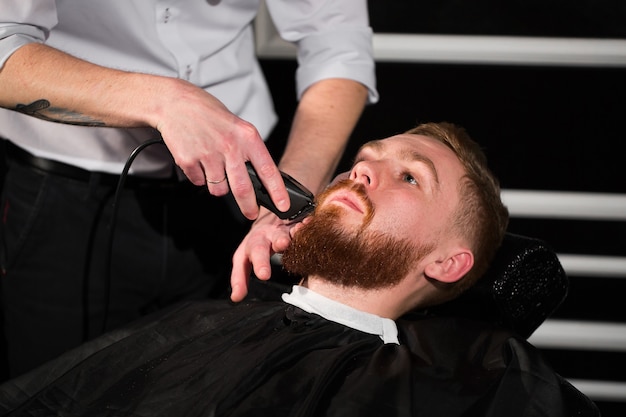 Le coiffeur rase la barbe masculine avec le couteau. Bel homme barbu se fait raser par un coiffeur au salon de coiffure