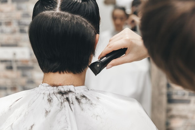 Le coiffeur redresse les cheveux de la fille après une courte coupe de cheveux