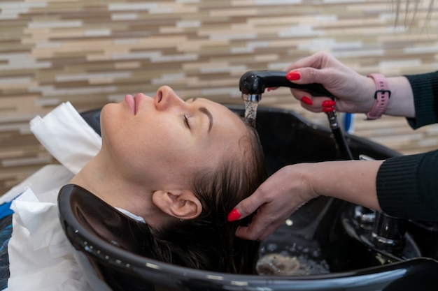 Le coiffeur rince les cheveux de la fille avant de la couper