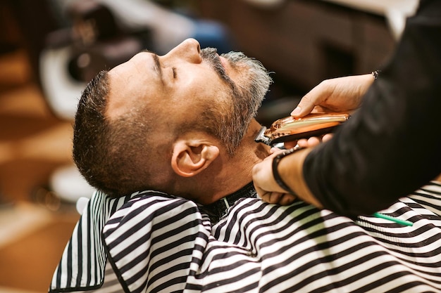 Photo le coiffeur taille la barbe du client dans son salon de coiffure dans un concept de beauté et de soins