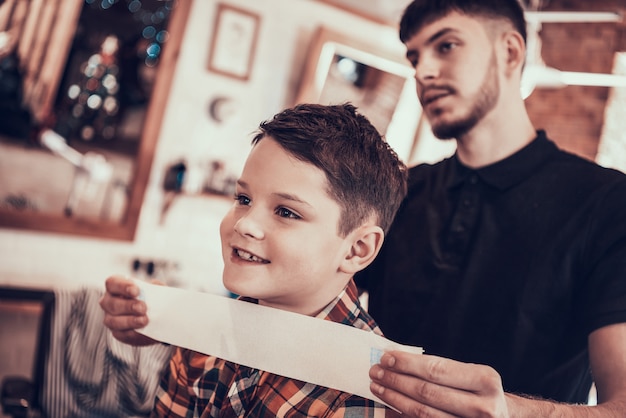 Le coiffeur tape la nuque de l'enfant avant de se couper les cheveux.