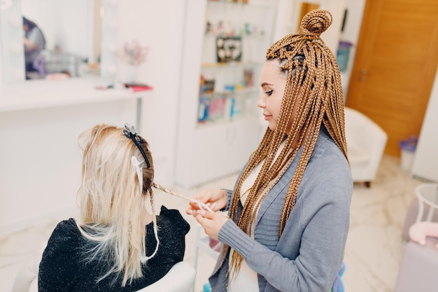 Coiffeur tressé afro tresses cheveux de cliente dans un salon de coiffure