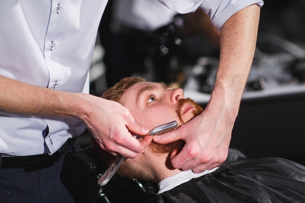 Coiffeur visite homme confiant en salon de coiffure.