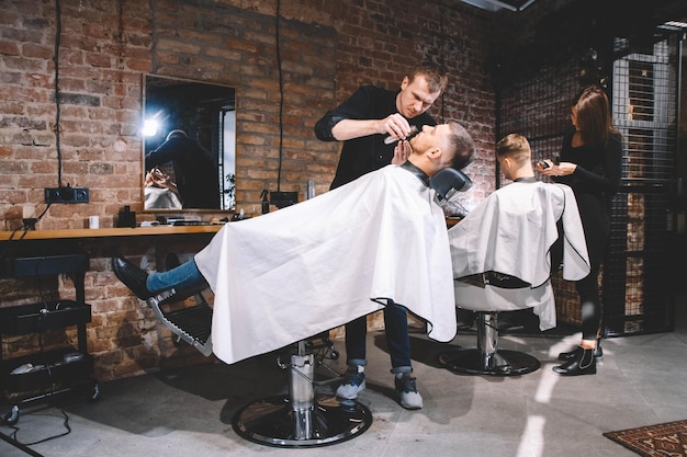 Les coiffeurs coupent leurs clients en salon de coiffure. Concept de publicité et de salon de coiffure