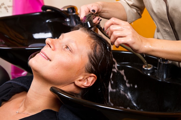 Coiffeurs laver à la main les cheveux des clientes dans le salon