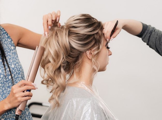 Une coiffeuse fait la coiffure de la mariée