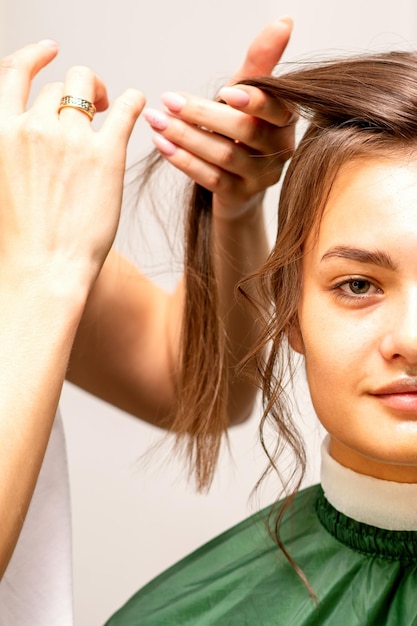 Coiffure mariée Une coiffeuse rend les cheveux coiffants pour la belle jeune femme caucasienne dans un salon de beauté