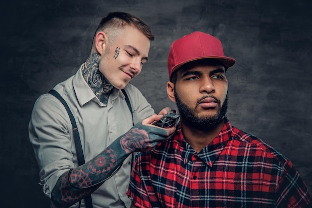 Coiffure tatouée coupant la barbe d'un homme hipster noir dans une casquette de baseball.