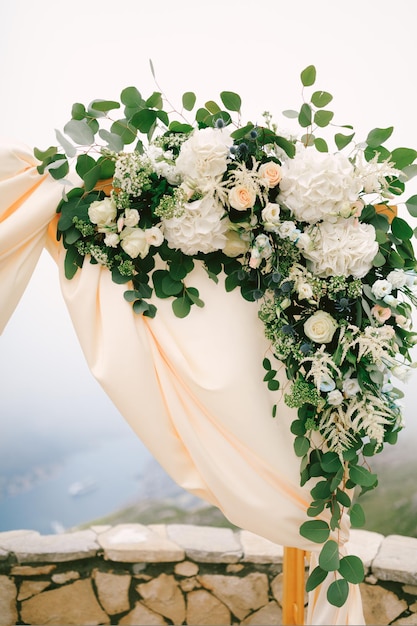 Coin d'une arche de mariage décorée de fleurs sur le fond de la baie