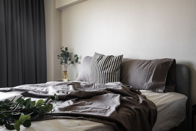 Coin de la chambre à coucher oreillers doux décoré avec table de nuit circulaire et cadre photo doré sur mur peint beige