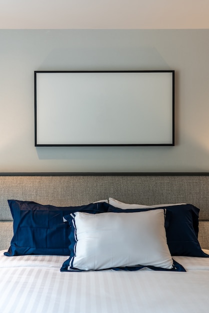 Photo coin de chambre élégant avec tête de lit en tissu gris et lit avec des oreillers moelleux avec un mur peint en bleu marine et blanc sur le fond / design intérieur confortable / intérieur moderne