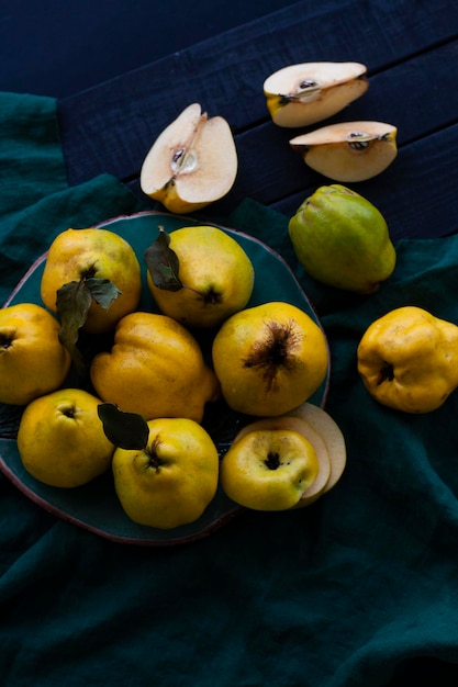 Coing tarte jaune se trouve sur une plaque sombre sur un tissu naturel sur un fond de bois noir Un fruit est coupé