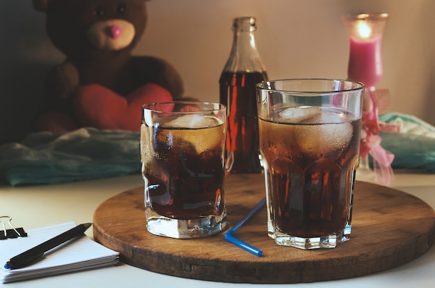 Cola Dans Un Verre Avec De La Glace Sur Le Fond D'une Bougie Allumée Et D'un Ours En Peluche.