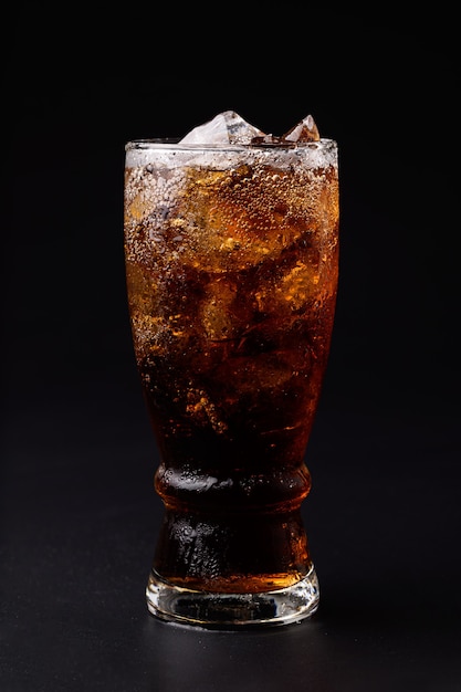 Cola en verre avec des glaçons clairs isolés sur fond noir