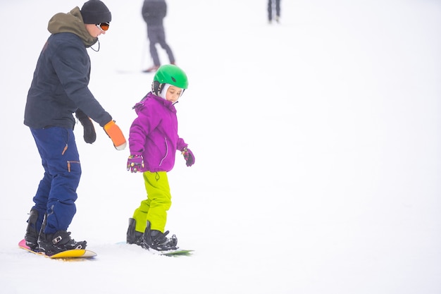 À Cold Winder Day à Mountain Ski Resort Père enseignant le snowboard à sa petite fille