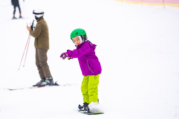 À Cold Winder Day à Mountain Ski Resort Père enseignant le snowboard à sa petite fille