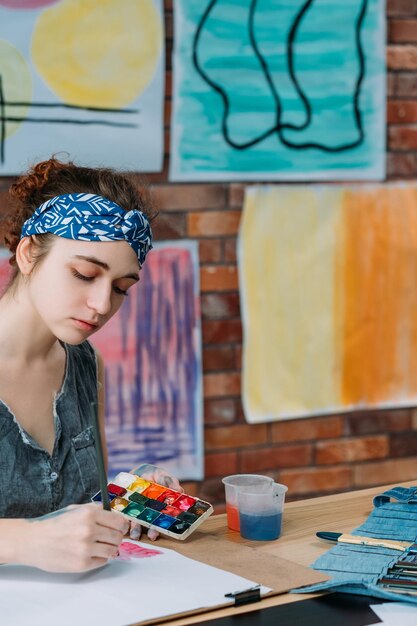 École d'art contemporain Portrait d'une dame inspirée peignant à l'aquarelle en studio Flou d'œuvres d'art colorées en arrière-plan