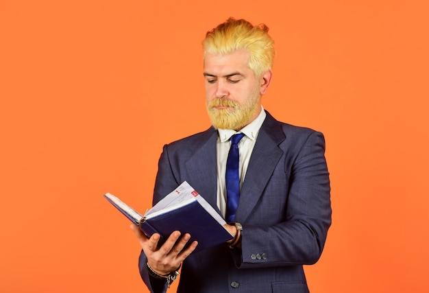 École de commerce éducation homme d'affaires sérieux tenir un cahier homme mûr barbe et cheveux teints livre de lecture vérifier ses notes horaire quotidien enseignant professionnel masculin après salon de coiffure