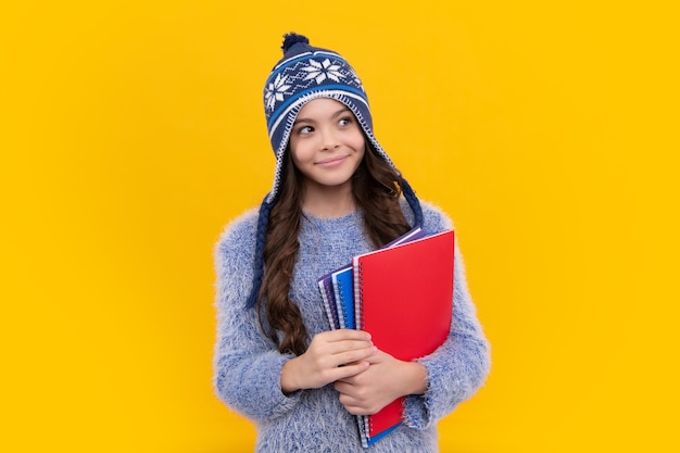 École d'hiver Écolière adolescente avec des livres en vêtements d'automne sur fond de studio isolé jaune