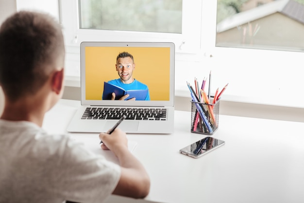 École à la maison grâce à l'enseignement à domicile en ligne. l'enfant est assis devant l'ordinateur